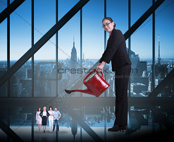 Composite image of businesswoman watering tiny business team