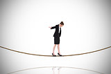 Composite image of businesswoman performing a balancing act on tightrope