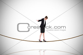 Composite image of businesswoman performing a balancing act on tightrope