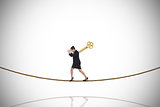 Composite image of wound up businesswoman gesturing on tightrope