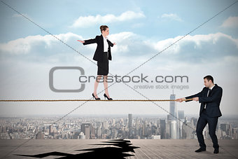 Young business man pulling a tightrope for businesswoman