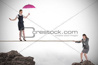 Young business woman pulling a tightrope for businesswoman