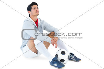Football player sitting with ball
