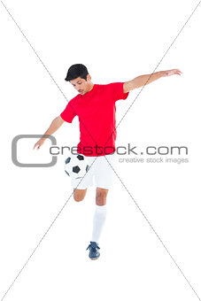 Football player in red kicking ball