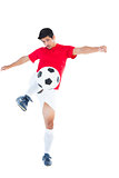 Football player in red kicking ball