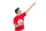 Football player in red holding ball and pointing