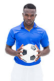 Football player in blue standing with the ball
