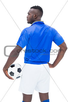 Football player in blue standing with the ball