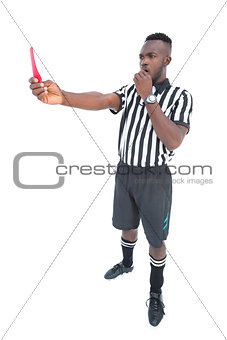 Serious referee showing red card blowing whistle