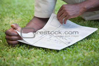Man relaxing in his garden reading newspaper
