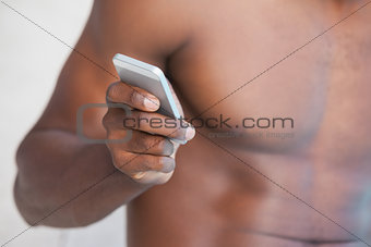 Shirtless man texting on phone