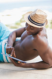 Happy shirtless man using his tablet pc