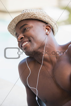 Shirtless man smiling and listening to music