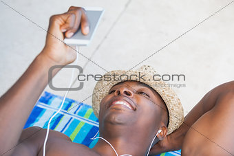 Shirtless man smiling and listening to music on smartphone