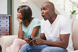 Bored woman sitting next to her boyfriend playing video games