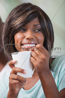 Happy woman sitting on couch having coffee
