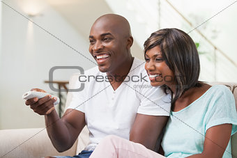 Happy couple watching television on sofa