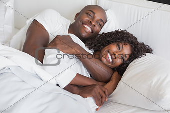 Happy couple cuddling together in bed