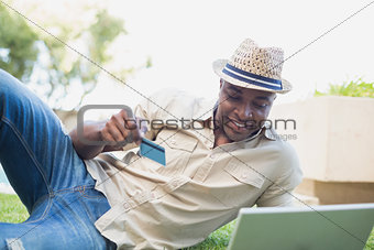 Handsome man relaxing in his garden using laptop to shop