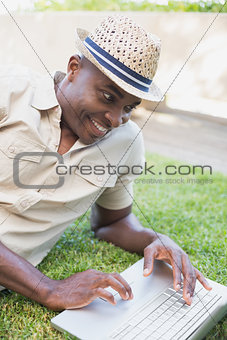 Smiling man relaxing in his garden using laptop