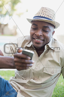 Smiling man relaxing in his garden texting on phone