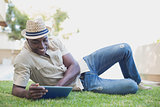 Smiling man relaxing in his garden using tablet pc