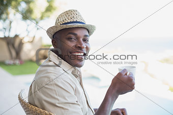 Smiling man relaxing in his garden having coffee