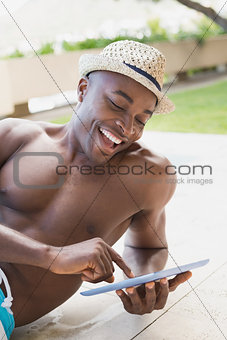 Handsome shirtless man using tablet pc poolside