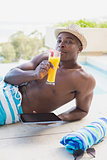 Handsome shirtless man using tablet pc poolside drinking cocktail