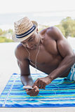 Handsome shirtless man listening to music poolside