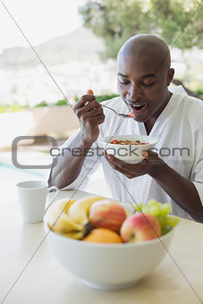 Handsome man in bathrobe having breakfast outside