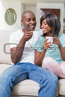 Happy couple relaxing on the couch having coffee