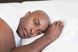 Unhappy man lying in bed