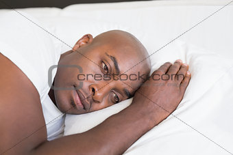 Unhappy man lying in bed