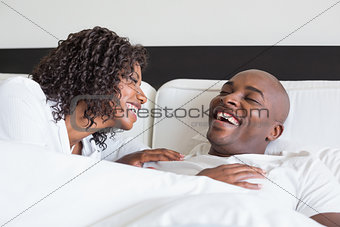 Happy couple cuddling in bed and laughing