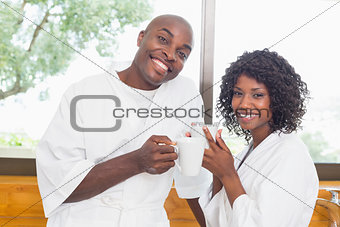 Happy couple having coffee together in bathrobes