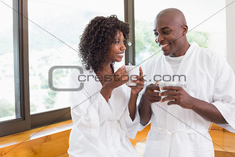 Happy couple having coffee together in bathrobes