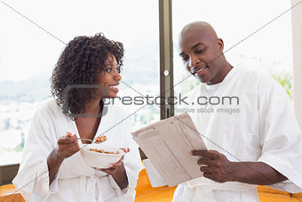 Happy couple having breakfast together in bathrobes