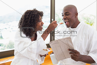 Happy couple having breakfast together in bathrobes