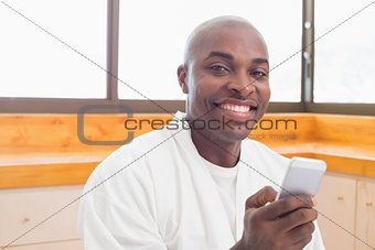 Happy man in bathrobe sending a text