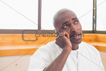 Serious man in bathrobe talking on phone
