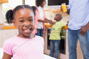 Cute little girl smiling at camera with family in background