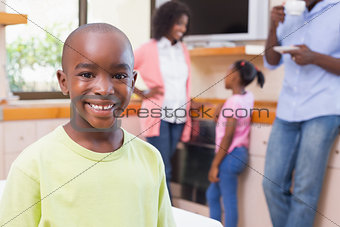 Cute little boy smiling at camera with family in background