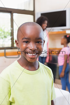 Cute little boy smiling at camera with family in background