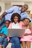 Happy family relaxing on the couch using laptop