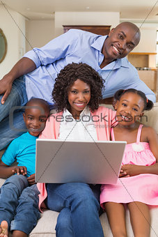 Happy family relaxing on the couch using laptop