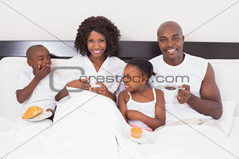 Happy family having breakfast in bed