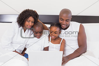 Happy family using laptop together in bed