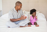 Father and baby girl sitting on bed together