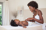 Happy mother with baby girl on changing table